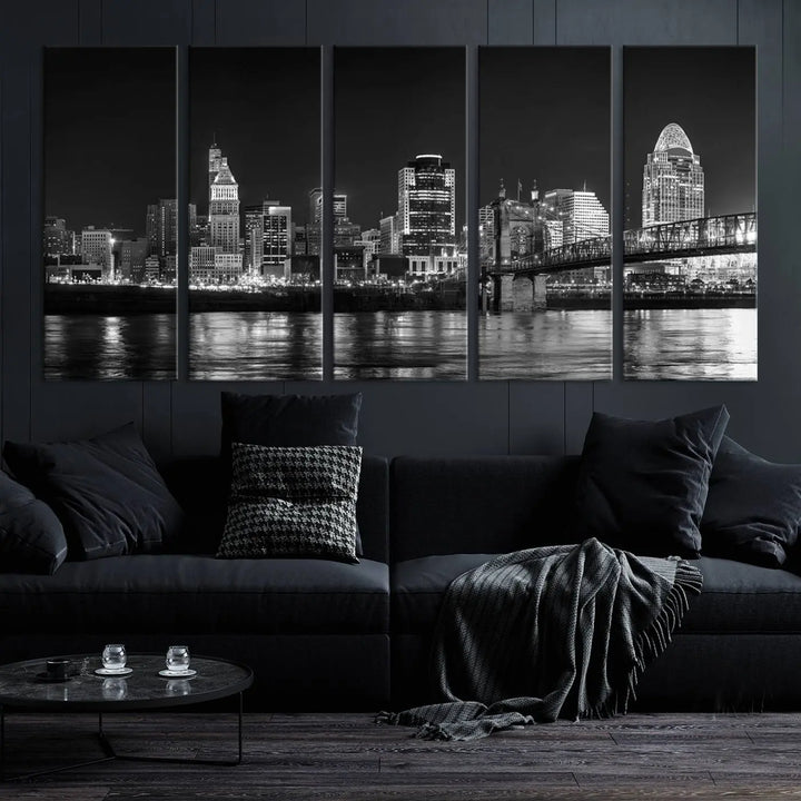 The Cincinnati City Lights Skyline Black and White Wall Art Cityscape Canvas Print elegantly adorns a modern living room. This museum-quality canvas triptych of a city skyline is enhanced by hand-assembled frames for added finesse, and you can enjoy free shipping on this stunning home addition.