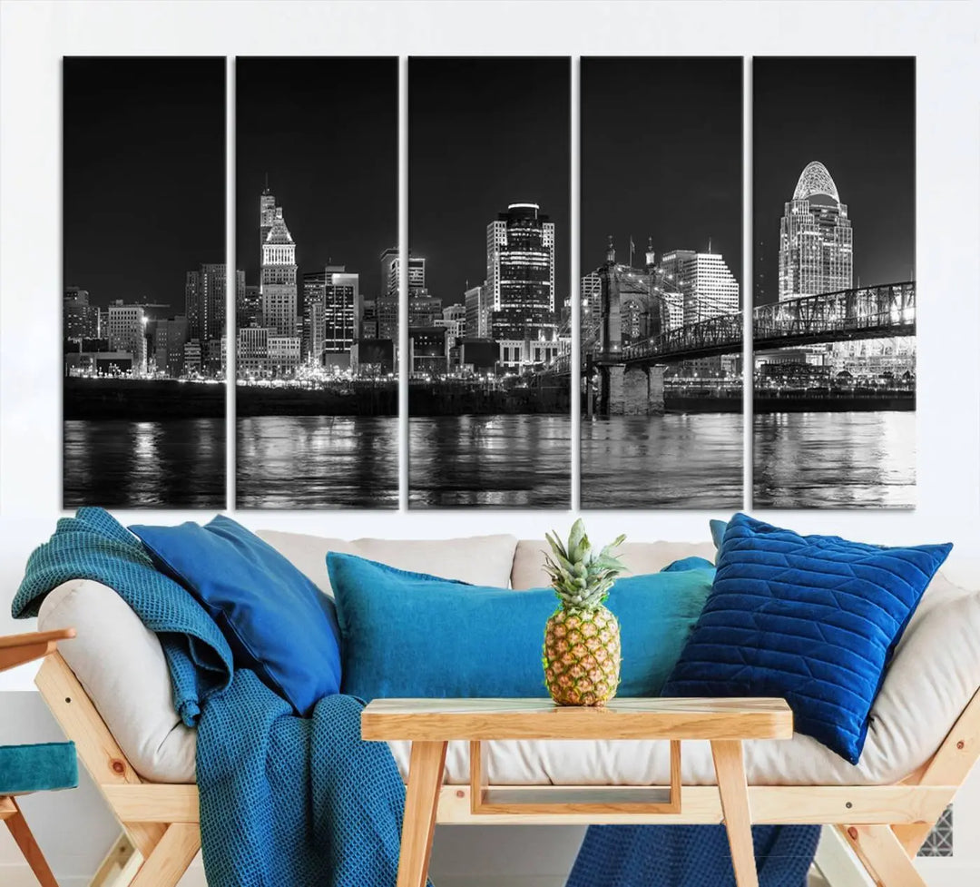 The Cincinnati City Lights Skyline Black and White Wall Art Cityscape Canvas Print elegantly adorns a modern living room. This museum-quality canvas triptych of a city skyline is enhanced by hand-assembled frames for added finesse, and you can enjoy free shipping on this stunning home addition.