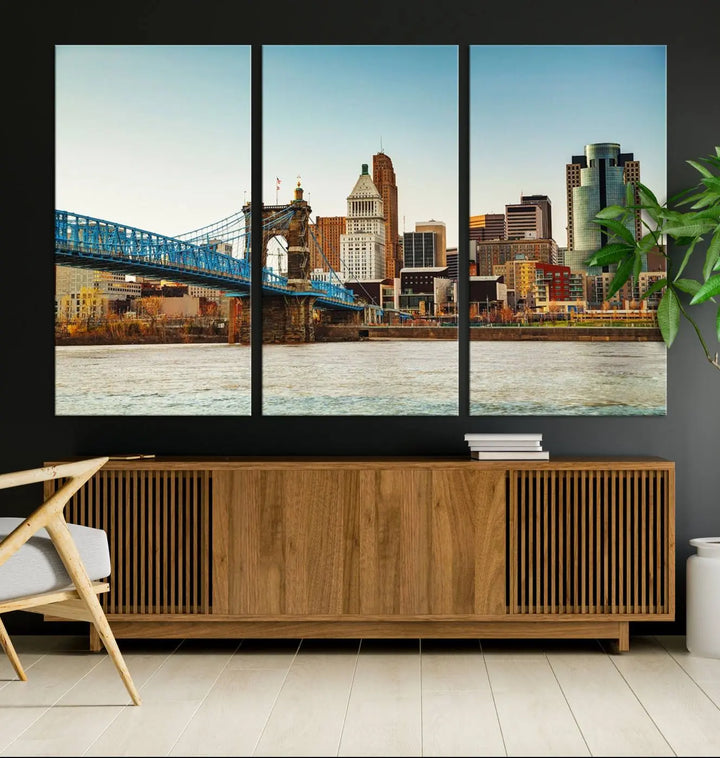 The Cincinnati City Morning Skyline Cityscape View Wall Art Canvas Print features three-panel museum-quality canvases depicting a city skyline with a bridge over a river. This gallery-wrapped artwork ensures an elegant finish and enduring beauty.