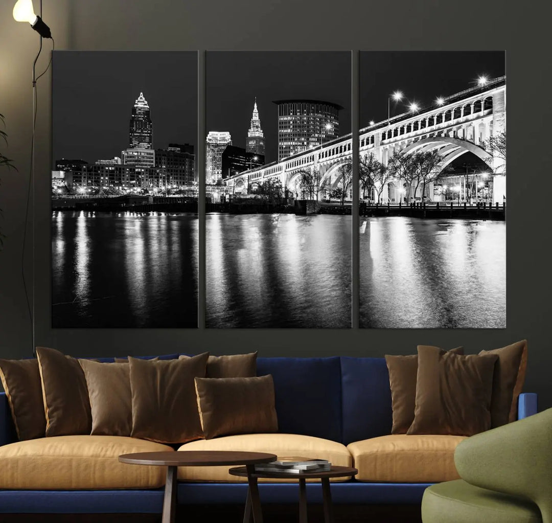 The "Cleveland Night Skyline Wall Art City Cityscape Canvas Print" is displayed in a black-and-white triptych on a gray wall. This gallery-wrapped artwork is printed on museum-quality canvas with a UV-protective coating, ensuring its striking details remain preserved for years.