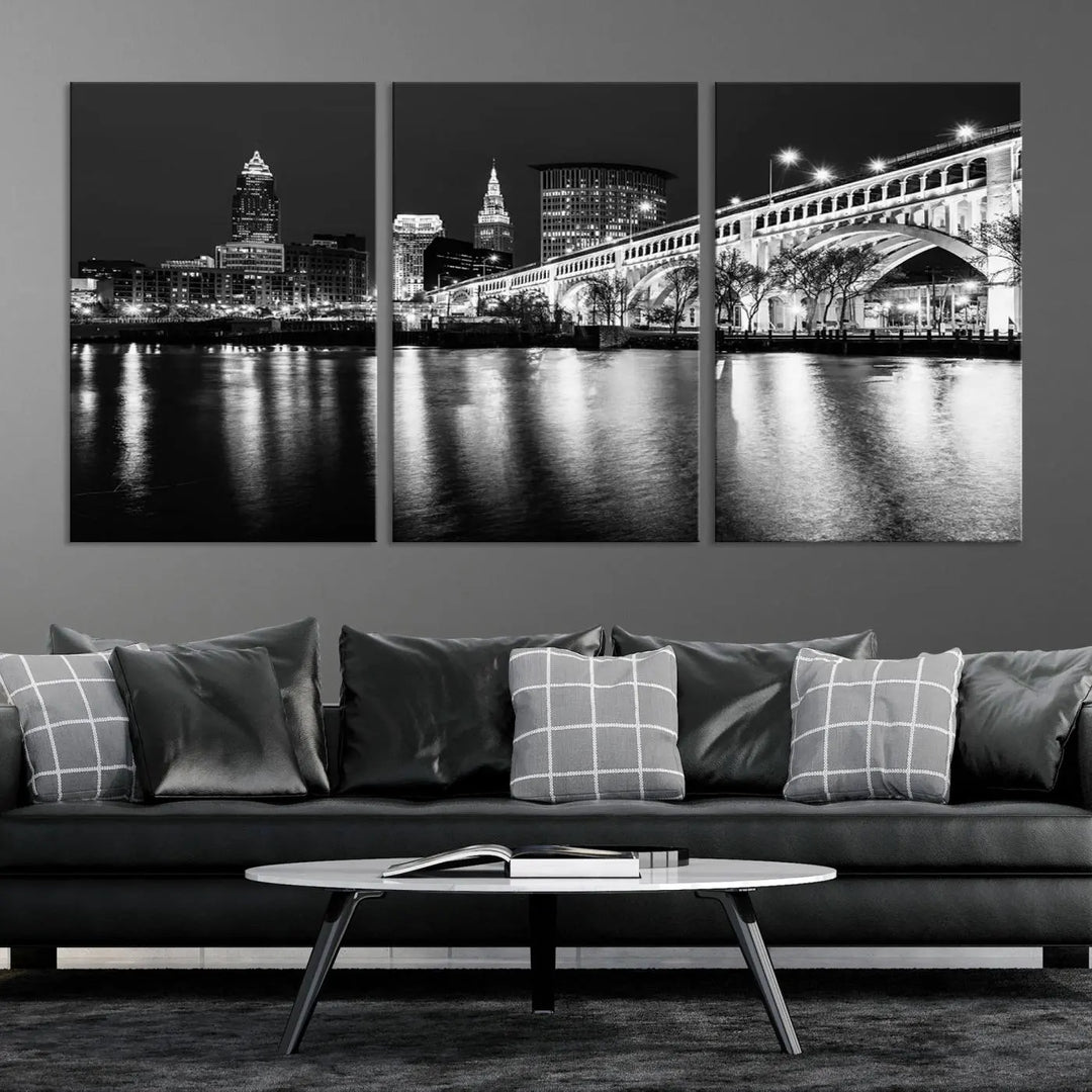 The "Cleveland Night Skyline Wall Art City Cityscape Canvas Print" is displayed in a black-and-white triptych on a gray wall. This gallery-wrapped artwork is printed on museum-quality canvas with a UV-protective coating, ensuring its striking details remain preserved for years.