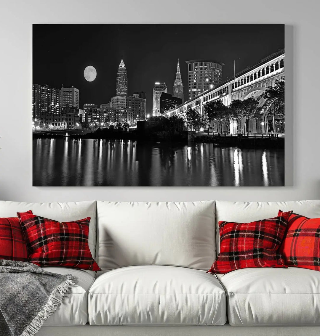 A modern living room features the "Cleveland Night Skyline Wall Art City Cityscape Canvas Print" on the wall, showcasing a moonlit skyline and river. It is professionally gallery wrapped on museum-quality canvas for enduring elegance.