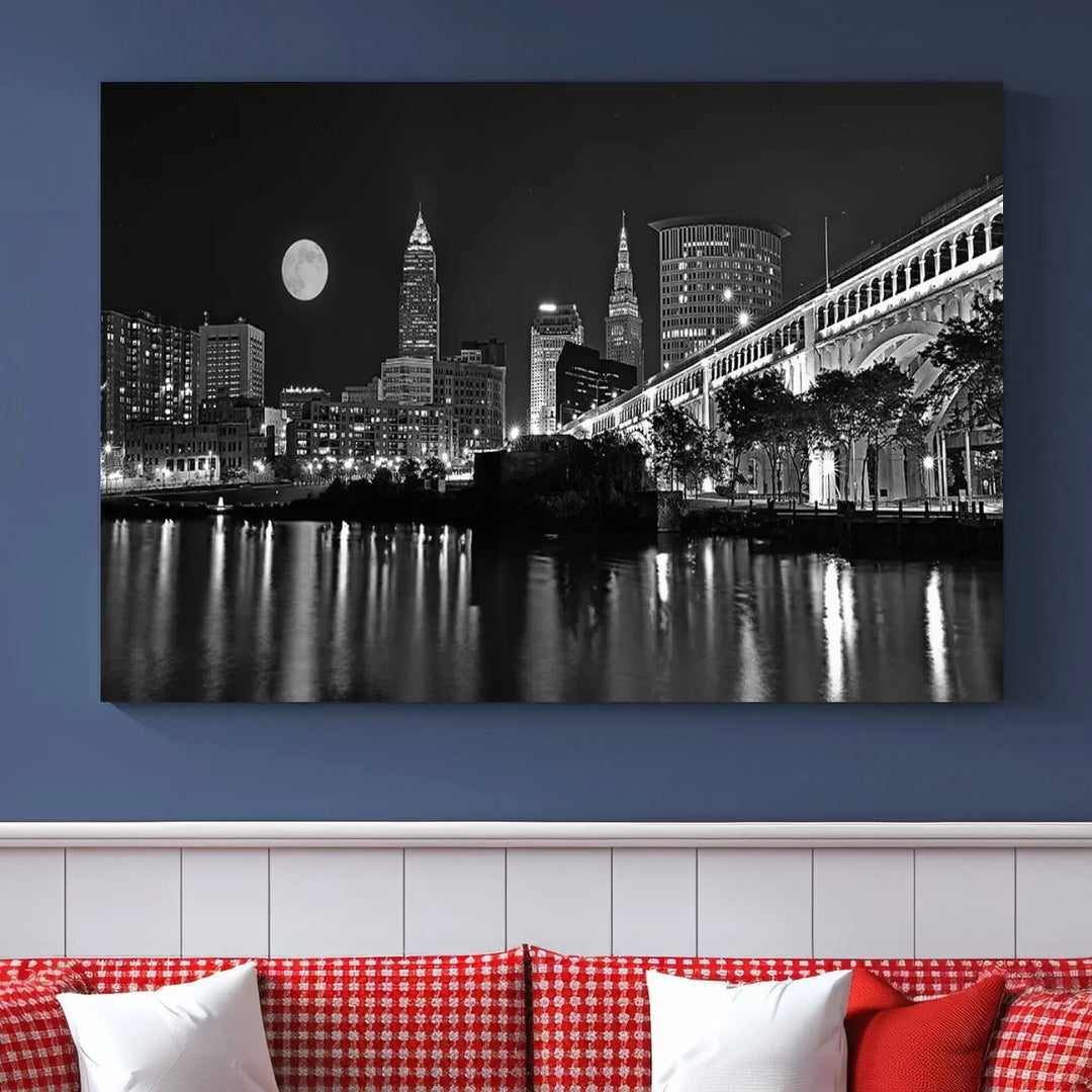 A modern living room features the "Cleveland Night Skyline Wall Art City Cityscape Canvas Print" on the wall, showcasing a moonlit skyline and river. It is professionally gallery wrapped on museum-quality canvas for enduring elegance.