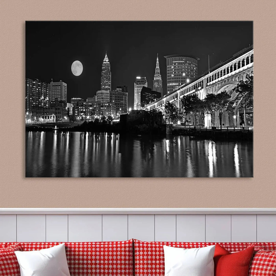 A modern living room features the "Cleveland Night Skyline Wall Art City Cityscape Canvas Print" on the wall, showcasing a moonlit skyline and river. It is professionally gallery wrapped on museum-quality canvas for enduring elegance.