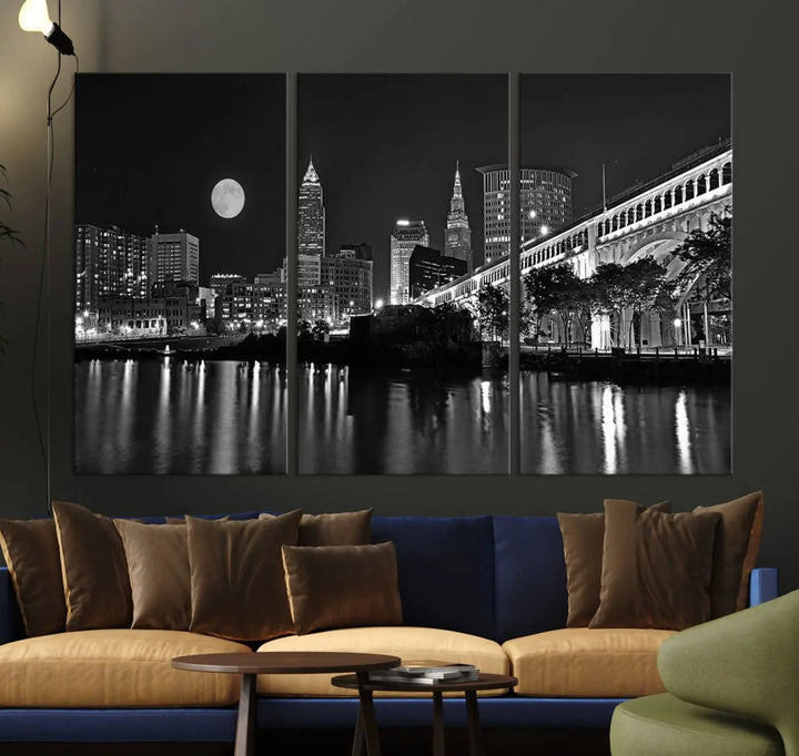 A modern living room features the "Cleveland Night Skyline Wall Art City Cityscape Canvas Print" on the wall, showcasing a moonlit skyline and river. It is professionally gallery wrapped on museum-quality canvas for enduring elegance.