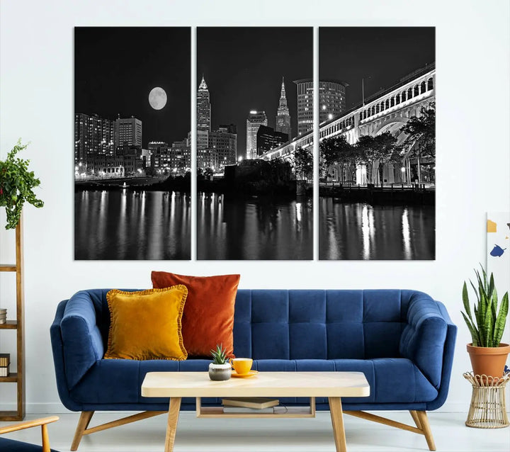 A modern living room features the "Cleveland Night Skyline Wall Art City Cityscape Canvas Print" on the wall, showcasing a moonlit skyline and river. It is professionally gallery wrapped on museum-quality canvas for enduring elegance.