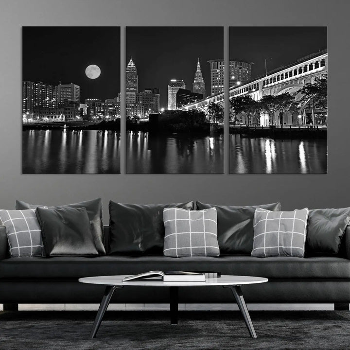 A modern living room features the "Cleveland Night Skyline Wall Art City Cityscape Canvas Print" on the wall, showcasing a moonlit skyline and river. It is professionally gallery wrapped on museum-quality canvas for enduring elegance.