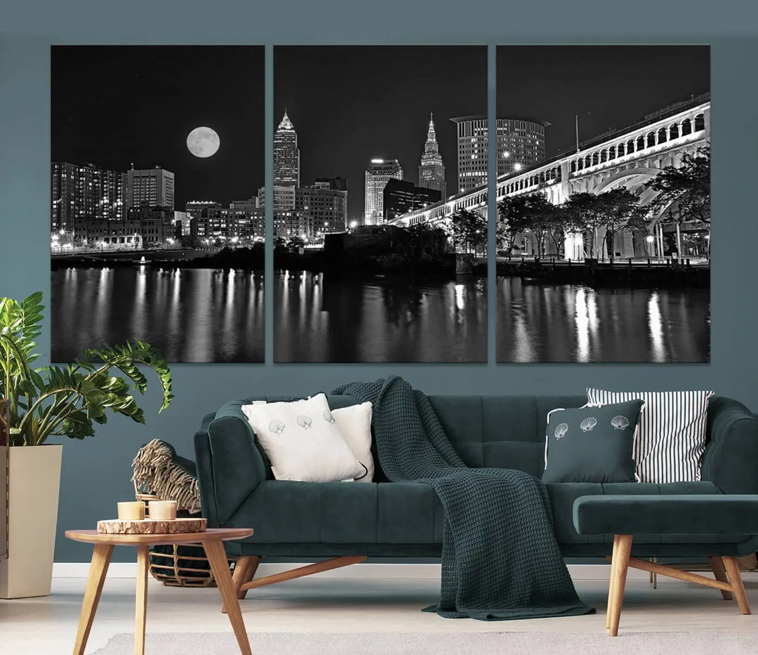 A modern living room features the "Cleveland Night Skyline Wall Art City Cityscape Canvas Print" on the wall, showcasing a moonlit skyline and river. It is professionally gallery wrapped on museum-quality canvas for enduring elegance.