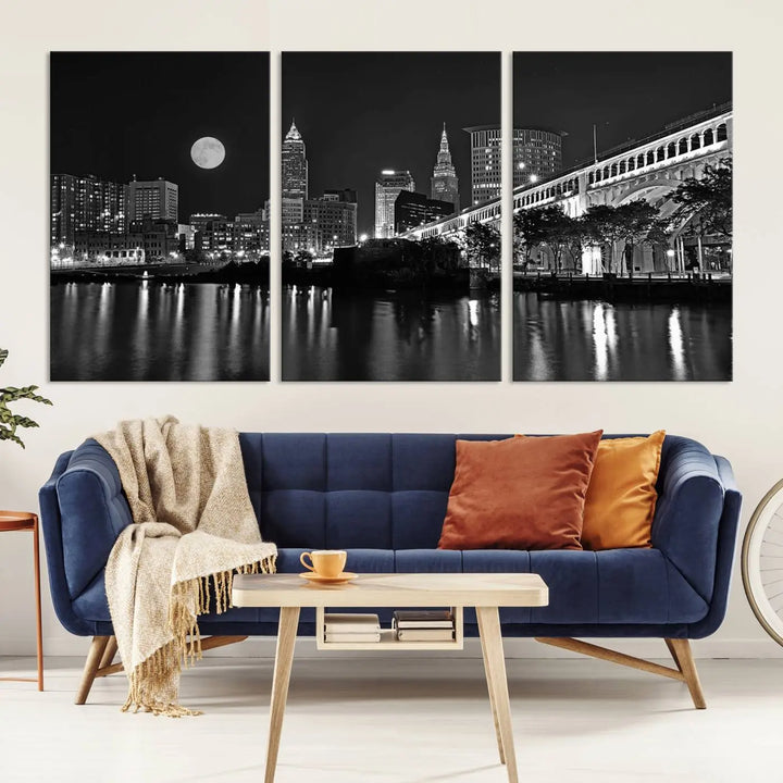 A modern living room features the "Cleveland Night Skyline Wall Art City Cityscape Canvas Print" on the wall, showcasing a moonlit skyline and river. It is professionally gallery wrapped on museum-quality canvas for enduring elegance.