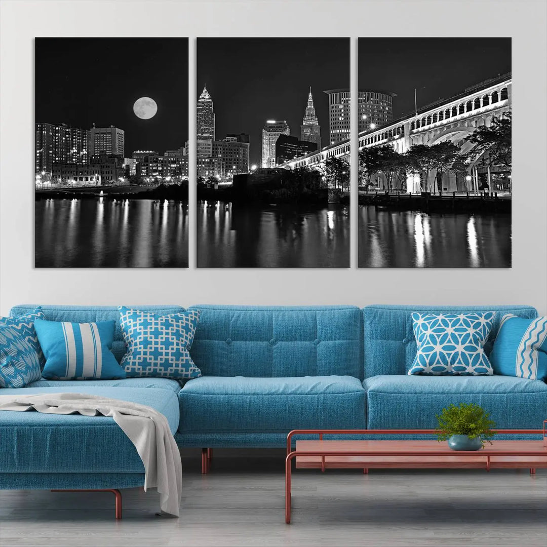 A modern living room features the "Cleveland Night Skyline Wall Art City Cityscape Canvas Print" on the wall, showcasing a moonlit skyline and river. It is professionally gallery wrapped on museum-quality canvas for enduring elegance.