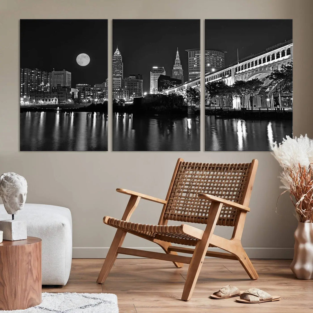 A modern living room features the "Cleveland Night Skyline Wall Art City Cityscape Canvas Print" on the wall, showcasing a moonlit skyline and river. It is professionally gallery wrapped on museum-quality canvas for enduring elegance.