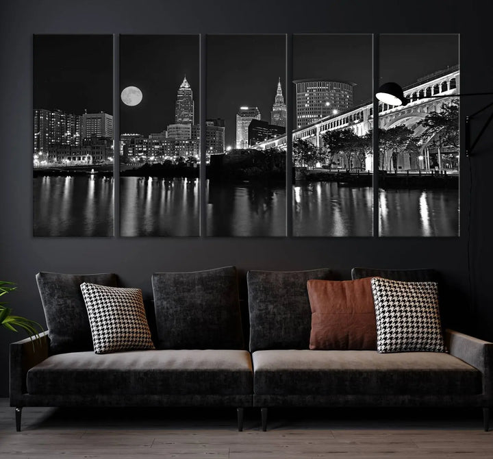 A modern living room features the "Cleveland Night Skyline Wall Art City Cityscape Canvas Print" on the wall, showcasing a moonlit skyline and river. It is professionally gallery wrapped on museum-quality canvas for enduring elegance.