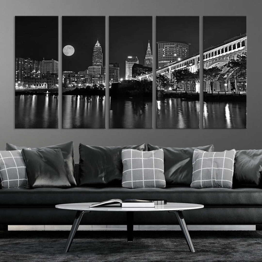 A modern living room features the "Cleveland Night Skyline Wall Art City Cityscape Canvas Print" on the wall, showcasing a moonlit skyline and river. It is professionally gallery wrapped on museum-quality canvas for enduring elegance.