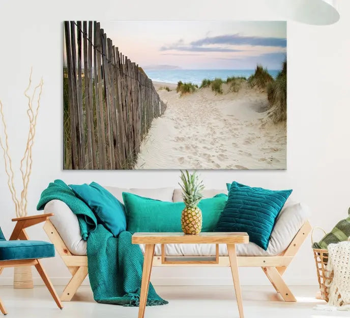 The Coastal Beach Fence Wall Art Ocean Landscape Canvas Print, featuring a triptych of a sandy beach scene with dunes and fences, is gallery wrapped on museum-quality canvas and displayed on a modern dark wall.