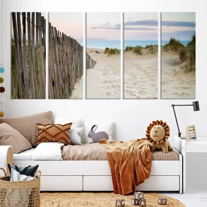 The Coastal Beach Fence Wall Art Ocean Landscape Canvas Print, featuring a triptych of a sandy beach scene with dunes and fences, is gallery wrapped on museum-quality canvas and displayed on a modern dark wall.