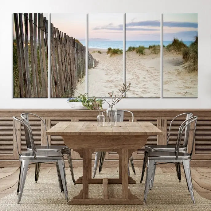 The Coastal Beach Fence Wall Art Ocean Landscape Canvas Print, featuring a triptych of a sandy beach scene with dunes and fences, is gallery wrapped on museum-quality canvas and displayed on a modern dark wall.