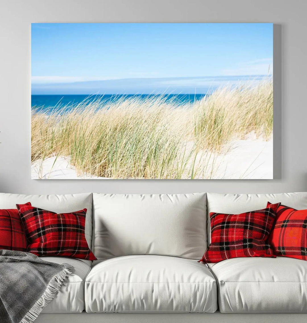 The Coastal Ocean Beach Wall Art Canvas Print, featuring a three-panel design with beach grass and an ocean view on museum-quality canvas, enhances the space in a modern living room. The artwork is ready to hang and comes with a UV-protective coating for enduring beauty.