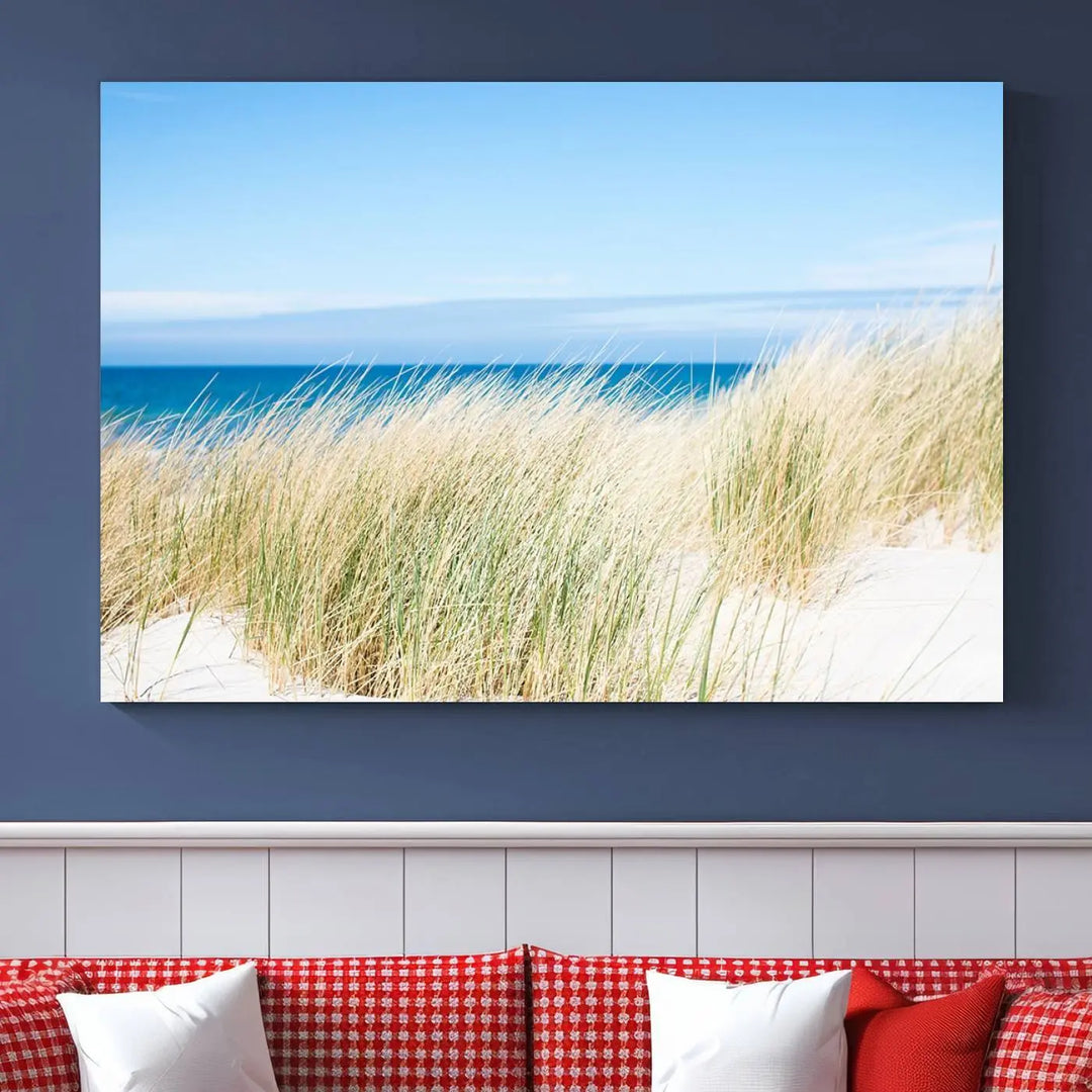 The Coastal Ocean Beach Wall Art Canvas Print, featuring a three-panel design with beach grass and an ocean view on museum-quality canvas, enhances the space in a modern living room. The artwork is ready to hang and comes with a UV-protective coating for enduring beauty.