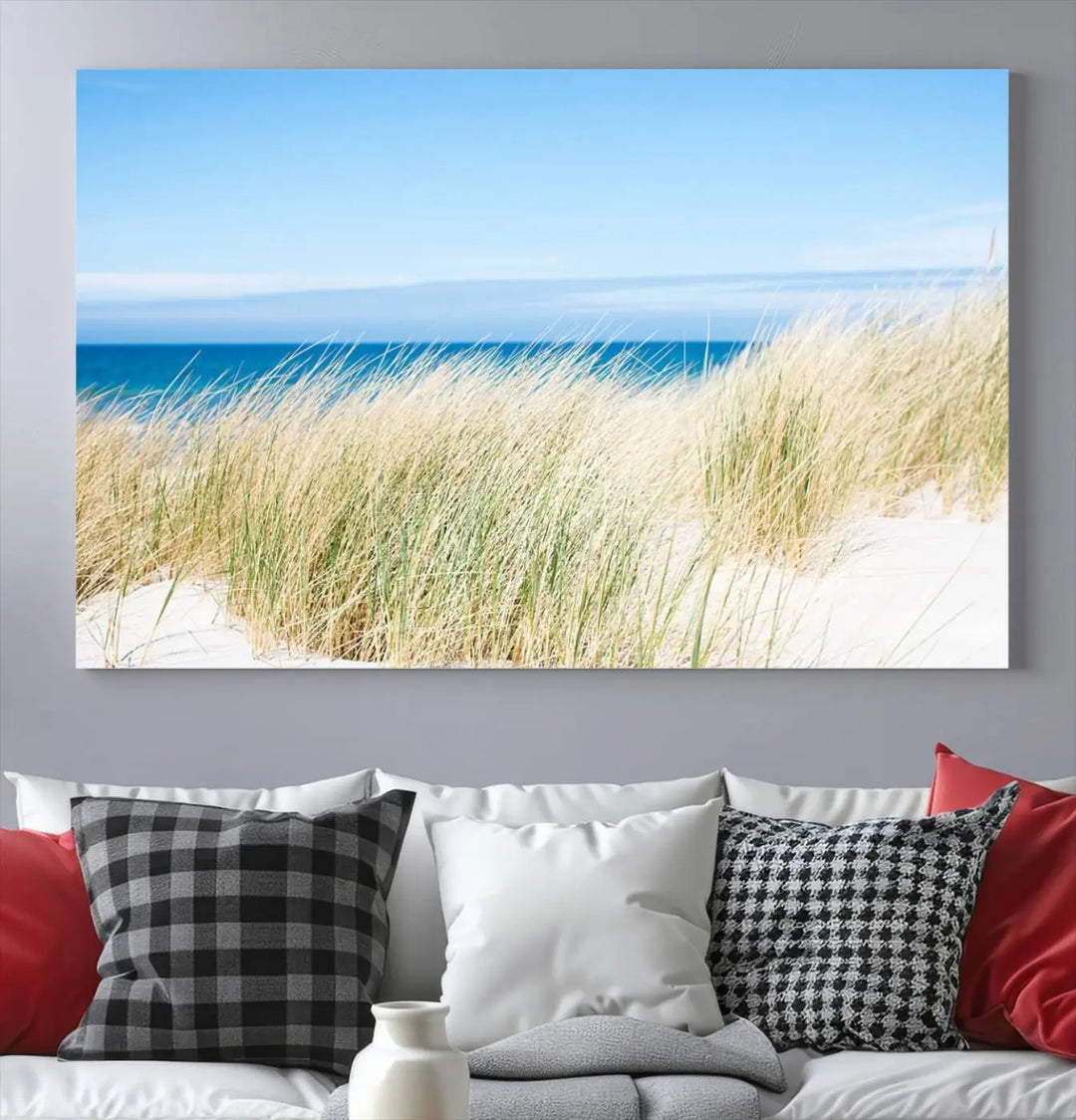 The Coastal Ocean Beach Wall Art Canvas Print, featuring a three-panel design with beach grass and an ocean view on museum-quality canvas, enhances the space in a modern living room. The artwork is ready to hang and comes with a UV-protective coating for enduring beauty.