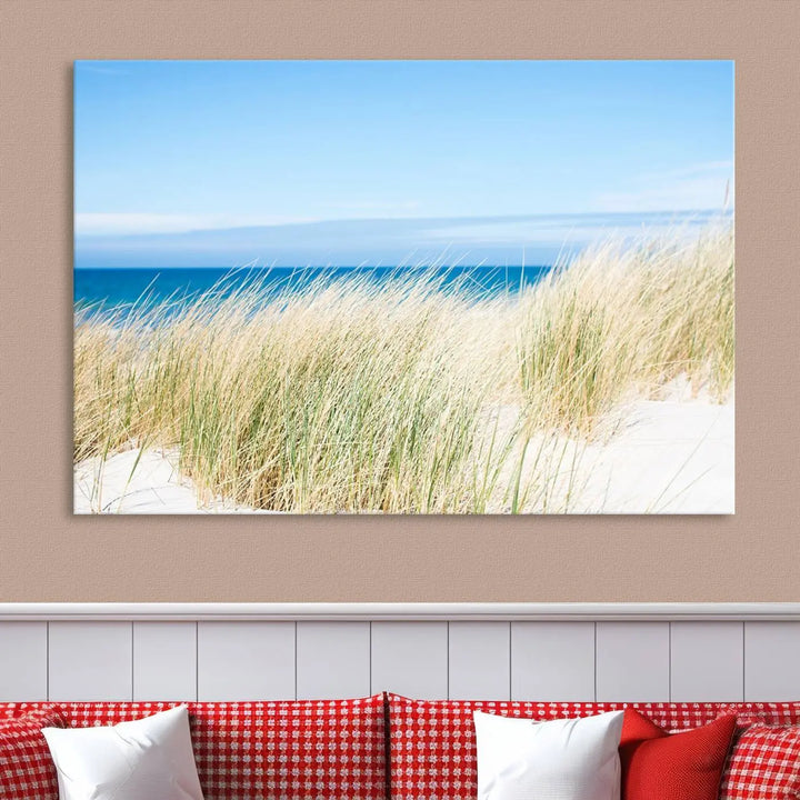 The Coastal Ocean Beach Wall Art Canvas Print, featuring a three-panel design with beach grass and an ocean view on museum-quality canvas, enhances the space in a modern living room. The artwork is ready to hang and comes with a UV-protective coating for enduring beauty.