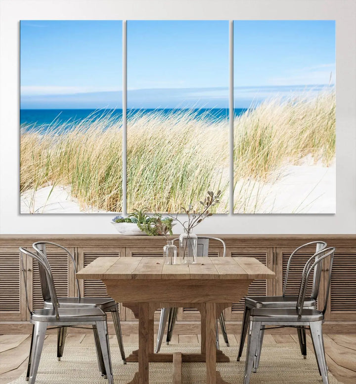 The Coastal Ocean Beach Wall Art Canvas Print, featuring a three-panel design with beach grass and an ocean view on museum-quality canvas, enhances the space in a modern living room. The artwork is ready to hang and comes with a UV-protective coating for enduring beauty.