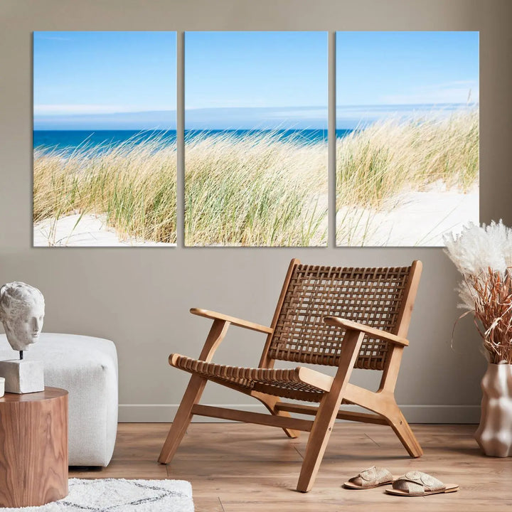 The Coastal Ocean Beach Wall Art Canvas Print, featuring a three-panel design with beach grass and an ocean view on museum-quality canvas, enhances the space in a modern living room. The artwork is ready to hang and comes with a UV-protective coating for enduring beauty.