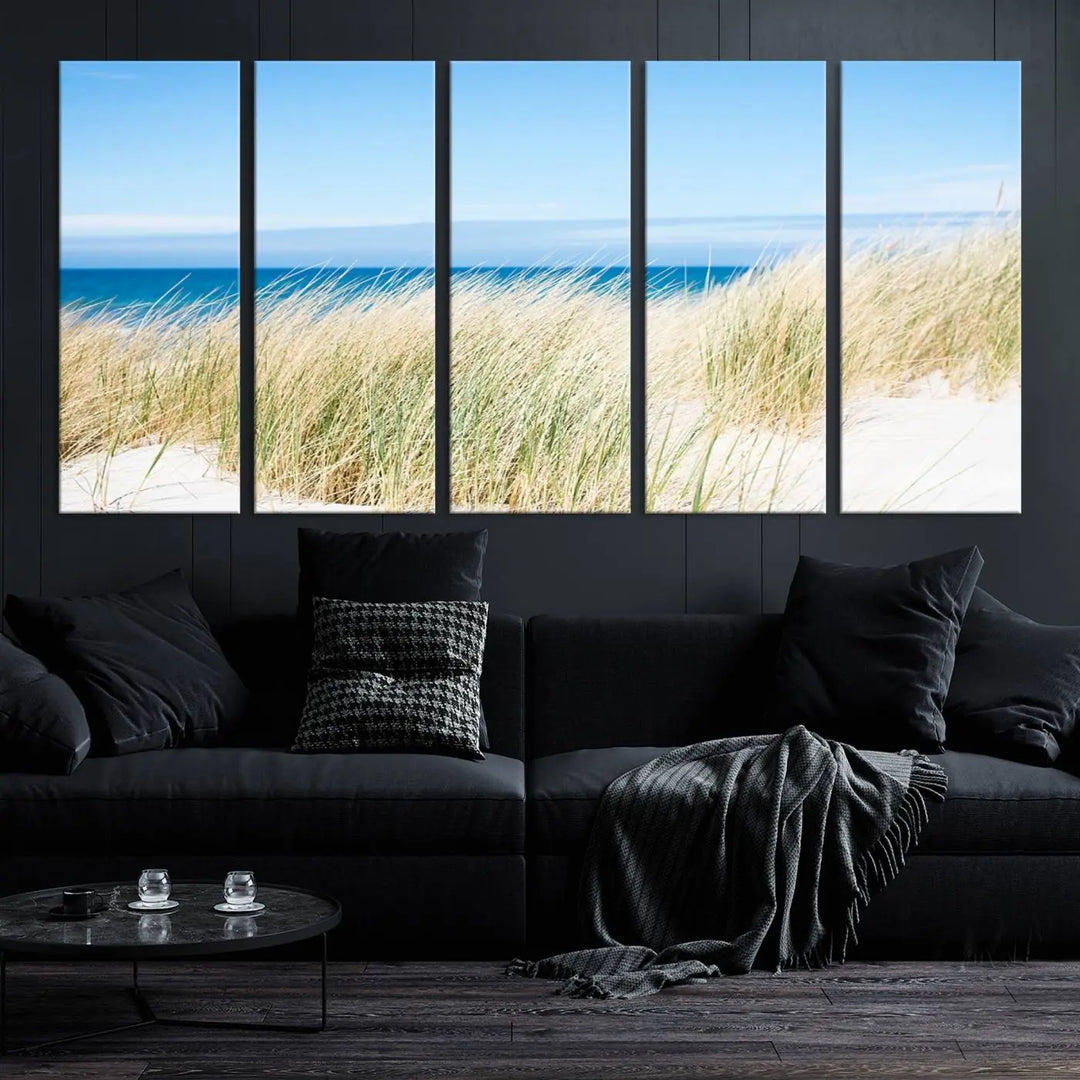 The Coastal Ocean Beach Wall Art Canvas Print, featuring a three-panel design with beach grass and an ocean view on museum-quality canvas, enhances the space in a modern living room. The artwork is ready to hang and comes with a UV-protective coating for enduring beauty.