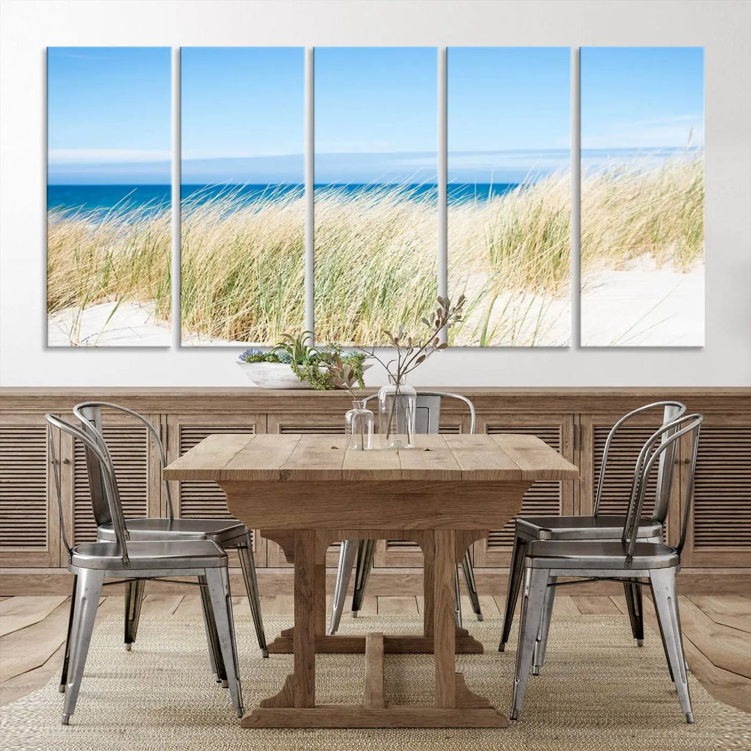 The Coastal Ocean Beach Wall Art Canvas Print, featuring a three-panel design with beach grass and an ocean view on museum-quality canvas, enhances the space in a modern living room. The artwork is ready to hang and comes with a UV-protective coating for enduring beauty.