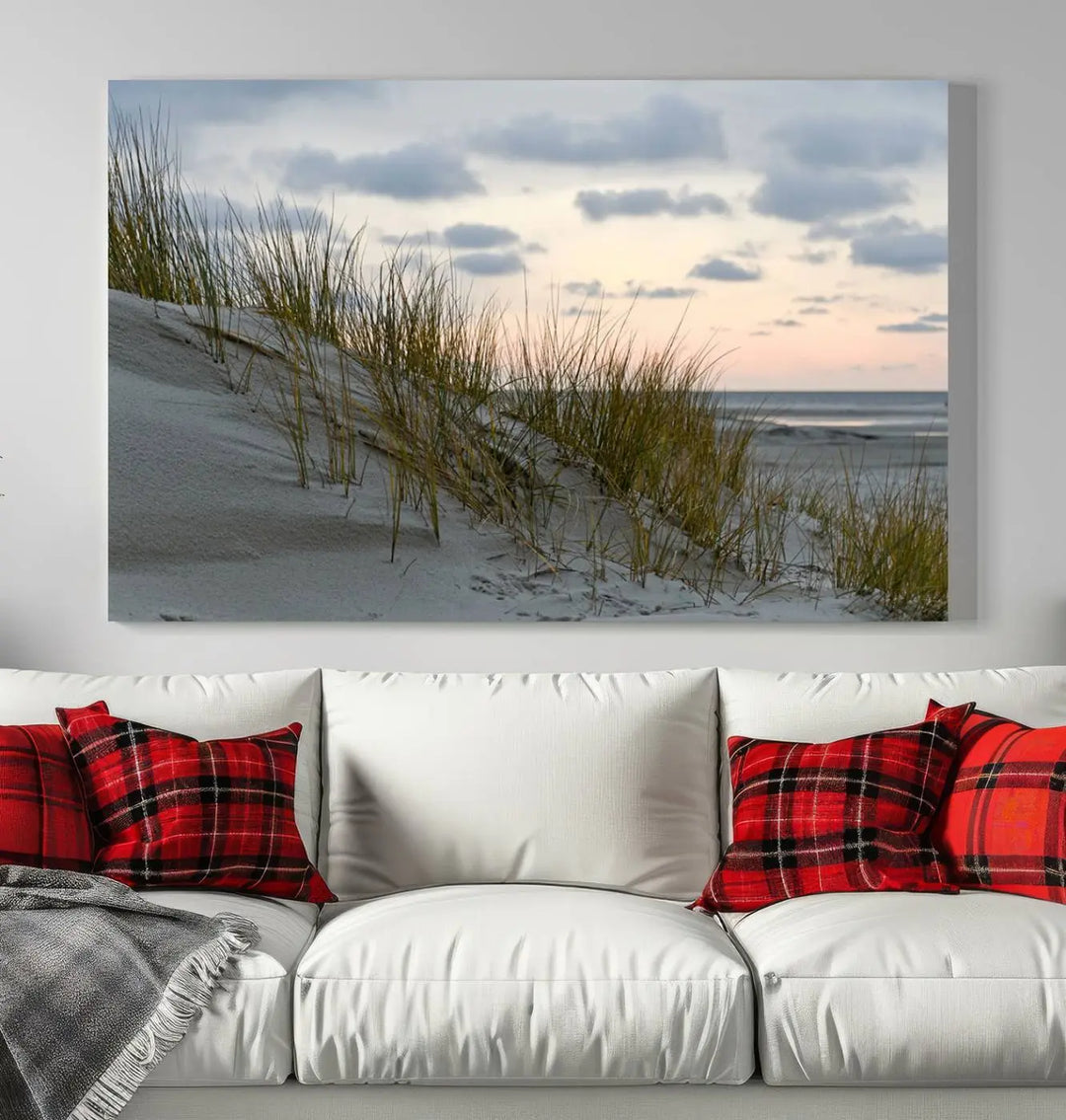 The Coastal Ocean Landscape Beach Wall Art Canvas Print is a triptych depicting sandy dunes and grass at sunset. It arrives ready to hang and is equipped with a UV-protective coating for lasting vibrancy and protection against fading sunlight.