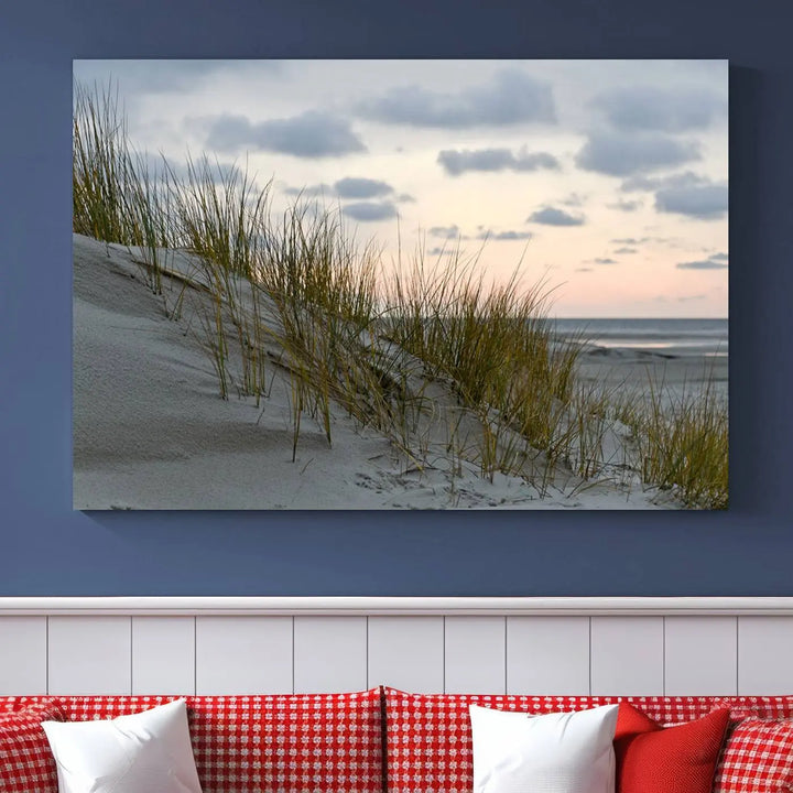 The Coastal Ocean Landscape Beach Wall Art Canvas Print is a triptych depicting sandy dunes and grass at sunset. It arrives ready to hang and is equipped with a UV-protective coating for lasting vibrancy and protection against fading sunlight.