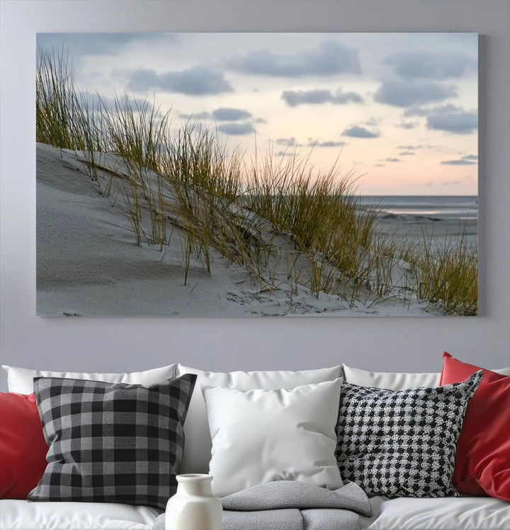 The Coastal Ocean Landscape Beach Wall Art Canvas Print is a triptych depicting sandy dunes and grass at sunset. It arrives ready to hang and is equipped with a UV-protective coating for lasting vibrancy and protection against fading sunlight.