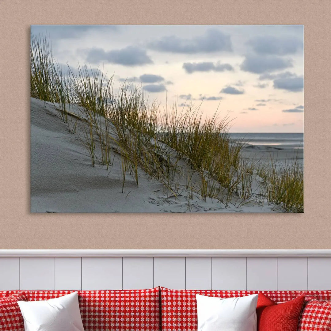 The Coastal Ocean Landscape Beach Wall Art Canvas Print is a triptych depicting sandy dunes and grass at sunset. It arrives ready to hang and is equipped with a UV-protective coating for lasting vibrancy and protection against fading sunlight.