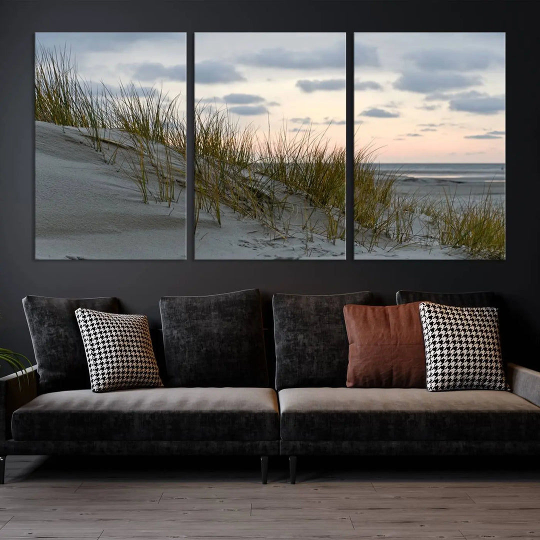 The Coastal Ocean Landscape Beach Wall Art Canvas Print is a triptych depicting sandy dunes and grass at sunset. It arrives ready to hang and is equipped with a UV-protective coating for lasting vibrancy and protection against fading sunlight.