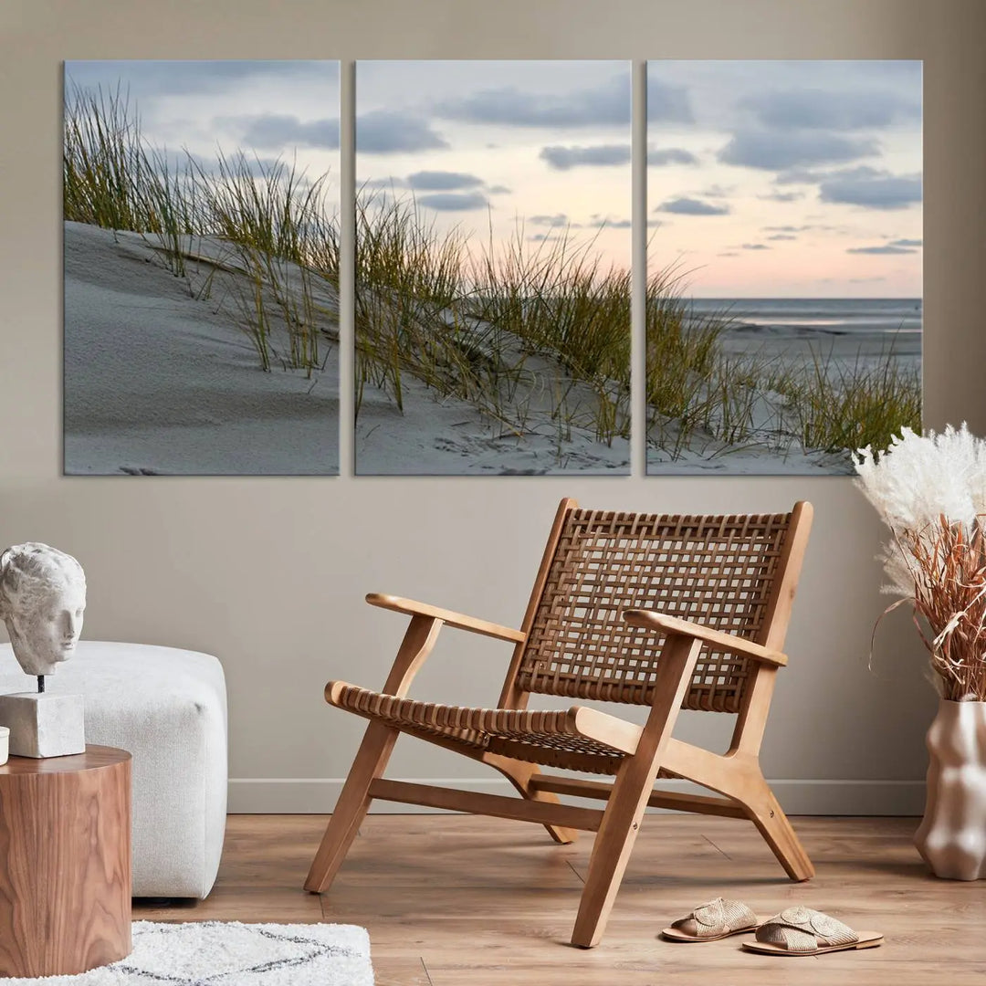 The Coastal Ocean Landscape Beach Wall Art Canvas Print is a triptych depicting sandy dunes and grass at sunset. It arrives ready to hang and is equipped with a UV-protective coating for lasting vibrancy and protection against fading sunlight.