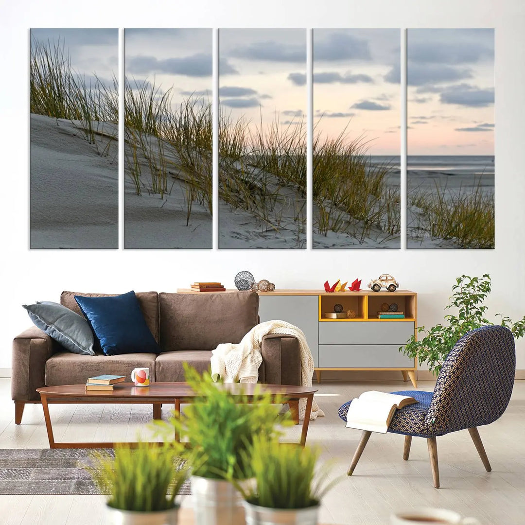 The Coastal Ocean Landscape Beach Wall Art Canvas Print is a triptych depicting sandy dunes and grass at sunset. It arrives ready to hang and is equipped with a UV-protective coating for lasting vibrancy and protection against fading sunlight.