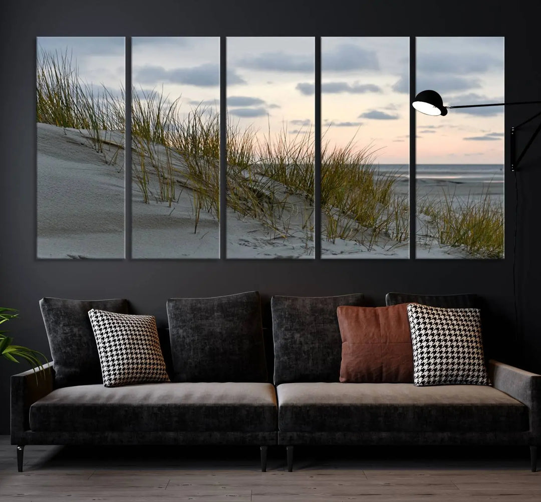 The Coastal Ocean Landscape Beach Wall Art Canvas Print is a triptych depicting sandy dunes and grass at sunset. It arrives ready to hang and is equipped with a UV-protective coating for lasting vibrancy and protection against fading sunlight.