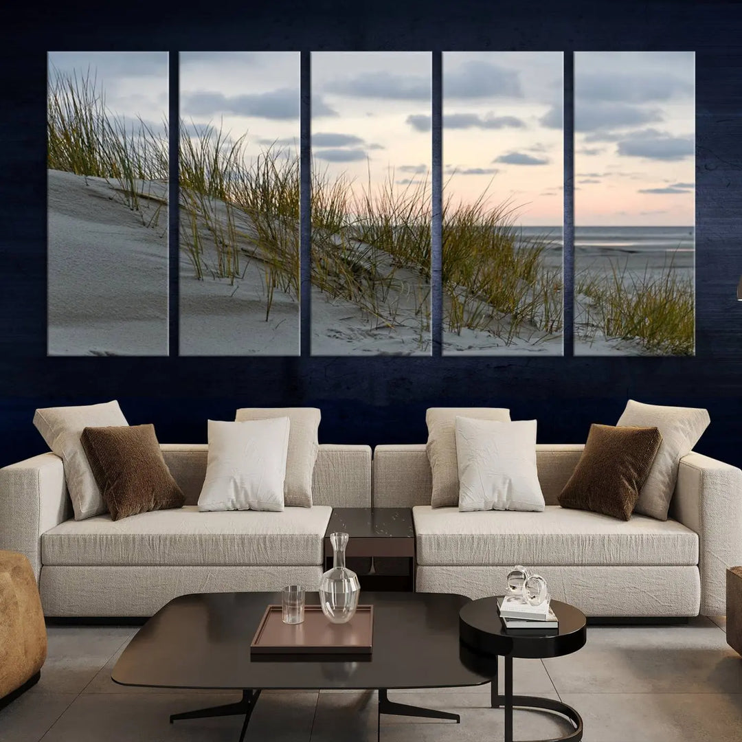 The Coastal Ocean Landscape Beach Wall Art Canvas Print is a triptych depicting sandy dunes and grass at sunset. It arrives ready to hang and is equipped with a UV-protective coating for lasting vibrancy and protection against fading sunlight.