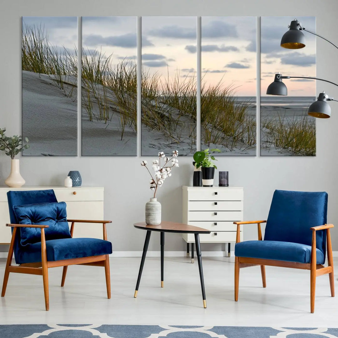 The Coastal Ocean Landscape Beach Wall Art Canvas Print is a triptych depicting sandy dunes and grass at sunset. It arrives ready to hang and is equipped with a UV-protective coating for lasting vibrancy and protection against fading sunlight.