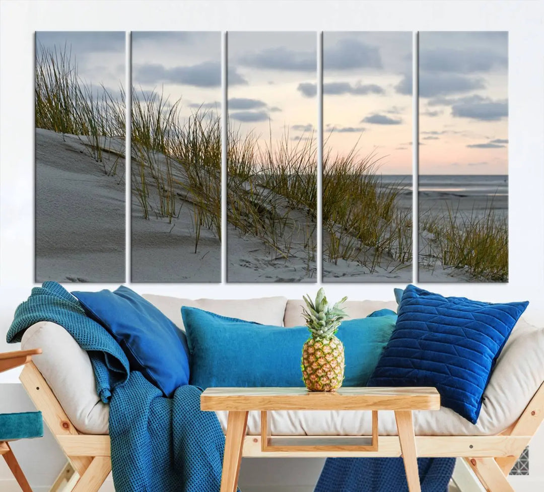 The Coastal Ocean Landscape Beach Wall Art Canvas Print is a triptych depicting sandy dunes and grass at sunset. It arrives ready to hang and is equipped with a UV-protective coating for lasting vibrancy and protection against fading sunlight.