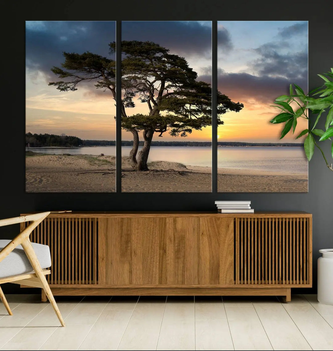 The room showcases the Coastal Sunset Wall Art Canvas Print, a triptych elegantly displayed on museum-quality polycotton canvas, depicting a serene beach sunset with a tree.