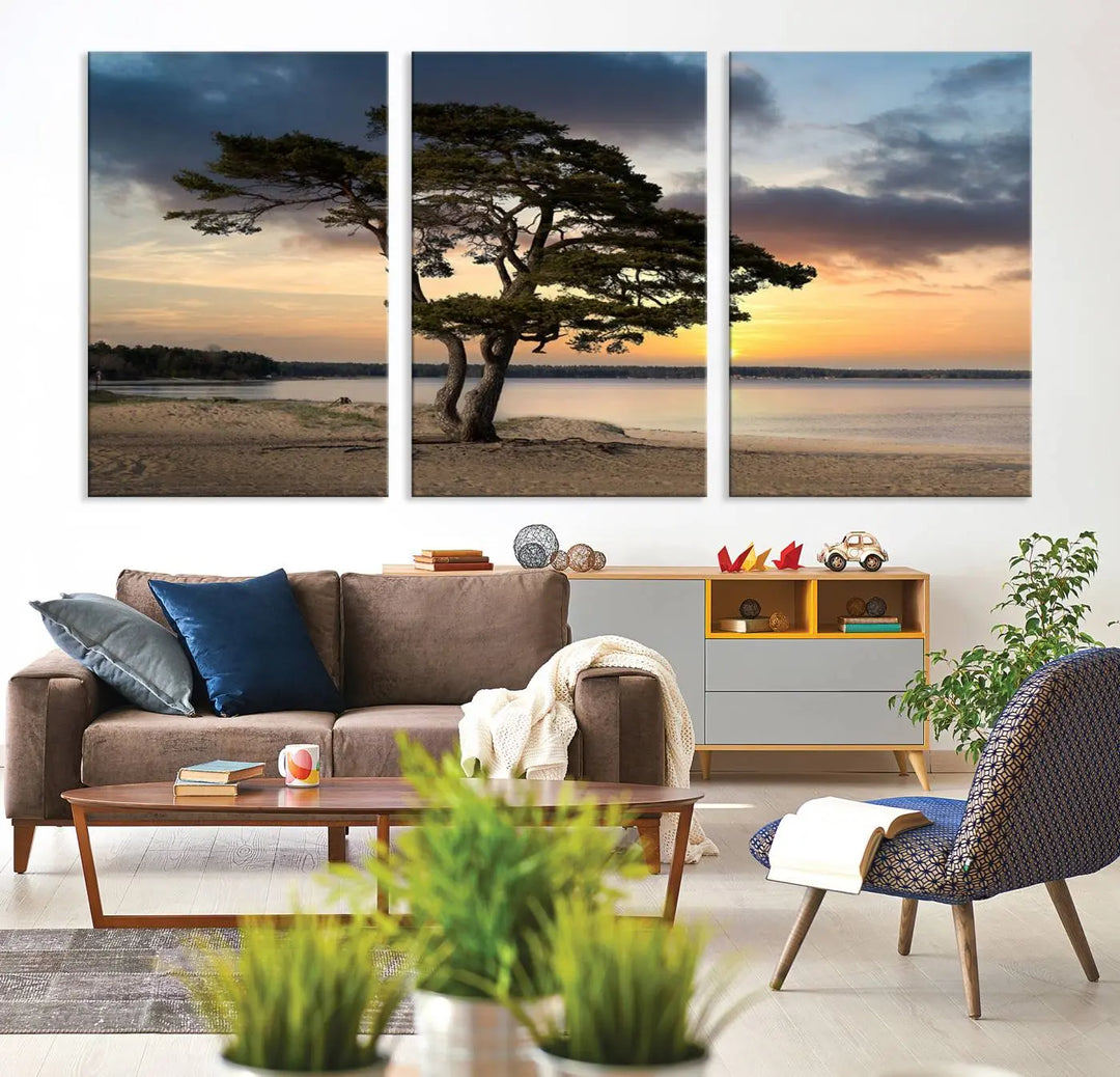 The room showcases the Coastal Sunset Wall Art Canvas Print, a triptych elegantly displayed on museum-quality polycotton canvas, depicting a serene beach sunset with a tree.