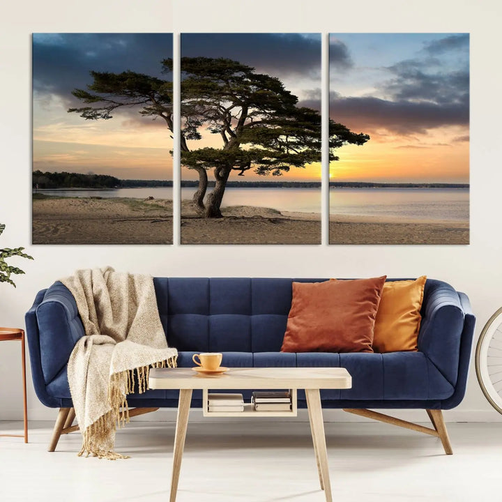 The room showcases the Coastal Sunset Wall Art Canvas Print, a triptych elegantly displayed on museum-quality polycotton canvas, depicting a serene beach sunset with a tree.