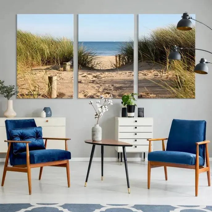 The Coastal Wall Art Beach Pathway Canvas Print creates a tranquil atmosphere, featuring a scenic sandy beach path lined with tall grass leading to the ocean.