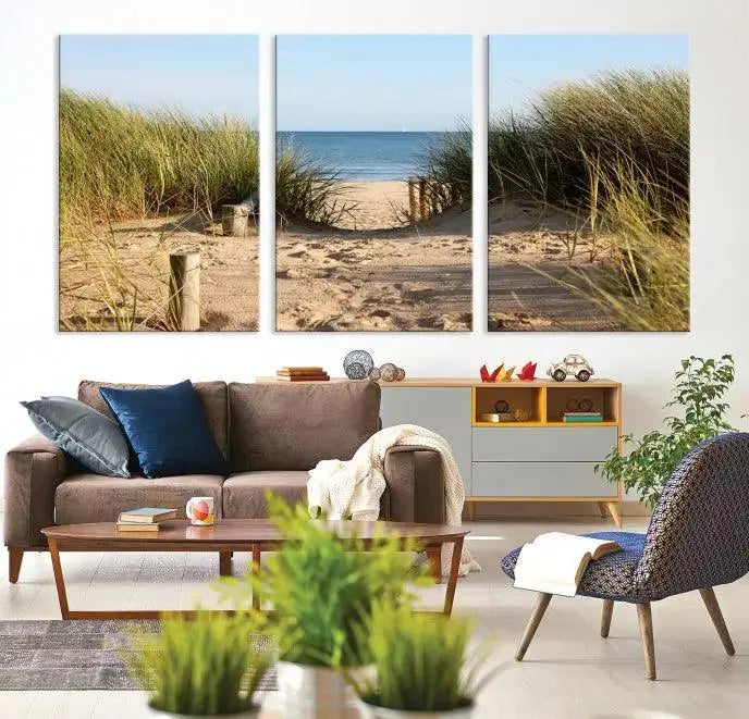 The Coastal Wall Art Beach Pathway Canvas Print creates a tranquil atmosphere, featuring a scenic sandy beach path lined with tall grass leading to the ocean.