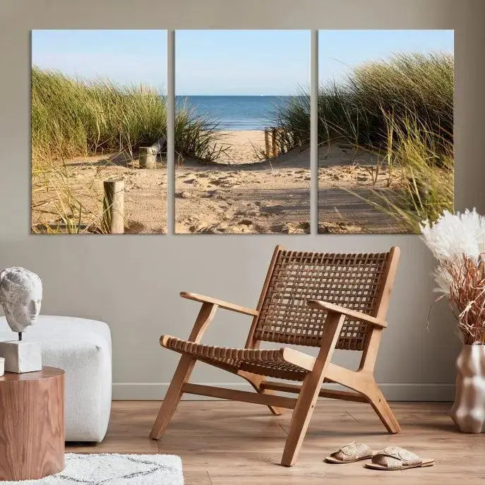 The Coastal Wall Art Beach Pathway Canvas Print creates a tranquil atmosphere, featuring a scenic sandy beach path lined with tall grass leading to the ocean.