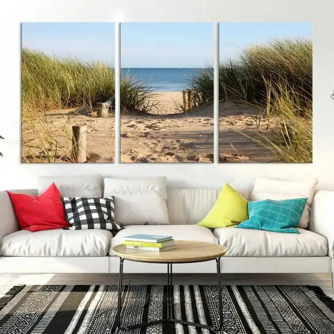 The Coastal Wall Art Beach Pathway Canvas Print creates a tranquil atmosphere, featuring a scenic sandy beach path lined with tall grass leading to the ocean.