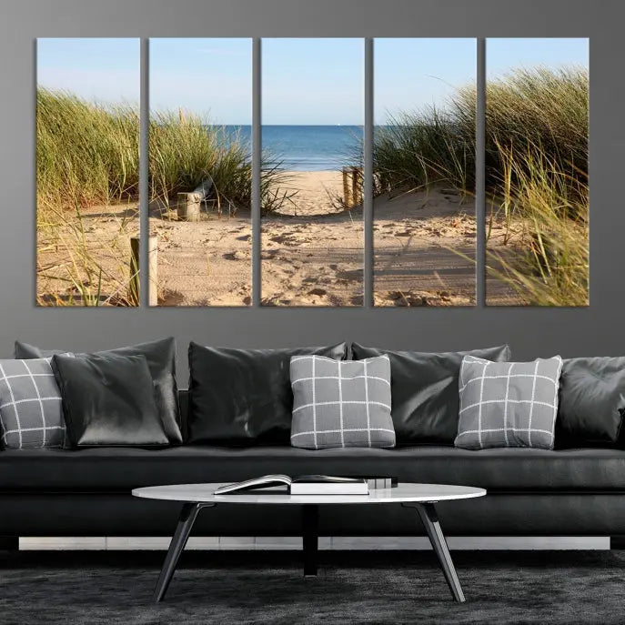 The Coastal Wall Art Beach Pathway Canvas Print creates a tranquil atmosphere, featuring a scenic sandy beach path lined with tall grass leading to the ocean.