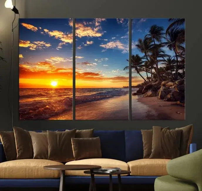 A Coastal Wall Art Beach at Sunset Canvas Print, featuring a triptych of a tropical sunset over the ocean with palm trees, graces the room.