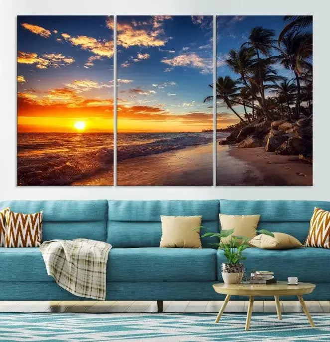 A Coastal Wall Art Beach at Sunset Canvas Print, featuring a triptych of a tropical sunset over the ocean with palm trees, graces the room.