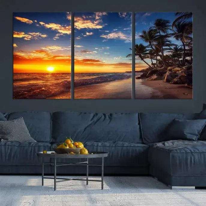 A Coastal Wall Art Beach at Sunset Canvas Print, featuring a triptych of a tropical sunset over the ocean with palm trees, graces the room.